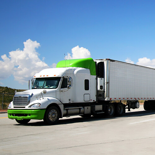 Green semi-truck driving on a road